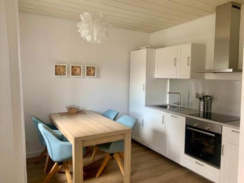 a kitchen with a wooden table and blue chairs at Ferienwohnungen Heidwaldhof in Merzig