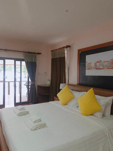 a bedroom with a large white bed with yellow pillows at Chaithalay Khanom Resort in Ban Phang Phrao