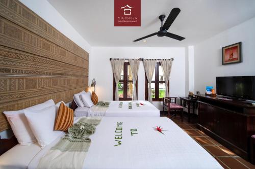 a bedroom with two beds and a flat screen tv at Victoria XiengThong Palace in Luang Prabang