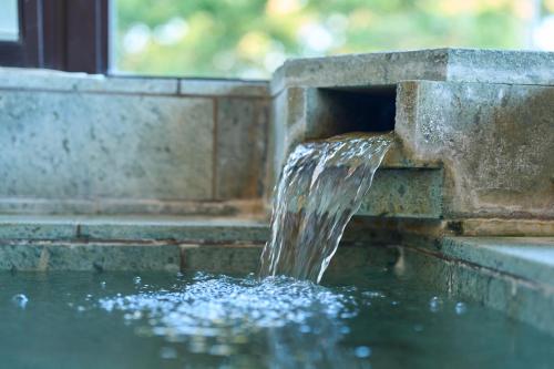 a stone fountain with water coming out of it at Suite Villa Panora Atami Sakurazawa in Atami