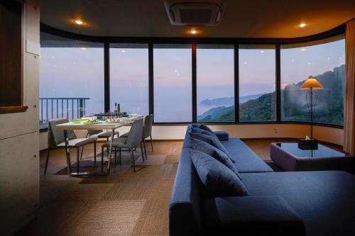 a living room with a couch and a table with a view at Suite Villa Panora Atami Sakurazawa in Atami