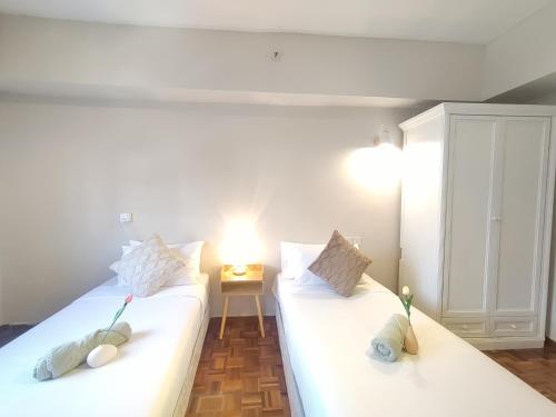 two white beds in a room with a lamp at Star Regency by Plush in Brinchang