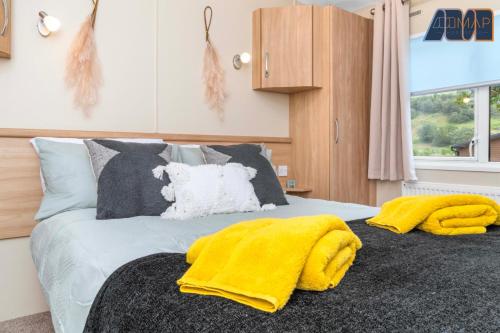 a bedroom with a bed with a yellow blanket on it at Loch Lomond - Ard Lui Lodge in Ardlui