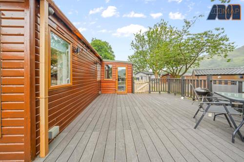 a cabin with a deck with a table and chairs at Loch Lomond - Ard Lui Lodge in Ardlui
