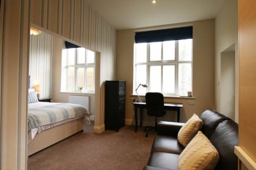 1 dormitorio con cama, escritorio y sofá en Hendford Apartments, en Yeovil