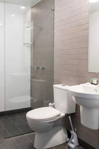 a bathroom with a toilet and a sink and a shower at The Bexley Motel in Sydney