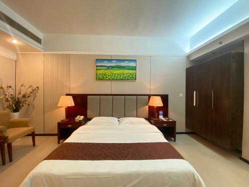 a bedroom with a large white bed and a chair at Yinfeng Hotel Guangzhou North Station Branch, Huacheng Road Subway Station Branch in Huadu