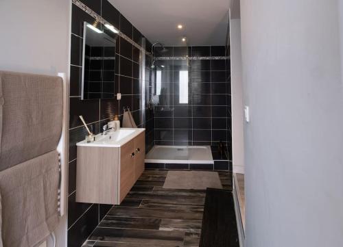 La salle de bains est pourvue d'une baignoire, d'un lavabo et de carrelage noir. dans l'établissement Le Cocon - Proche Gare Châteaucreux-, à Saint-Étienne