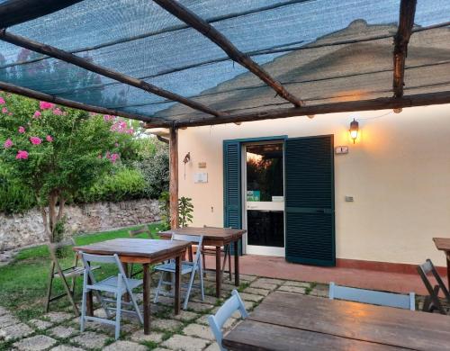 a patio with wooden tables and chairs under a pergola at Agriturismo le colline di Capalbio in Capalbio