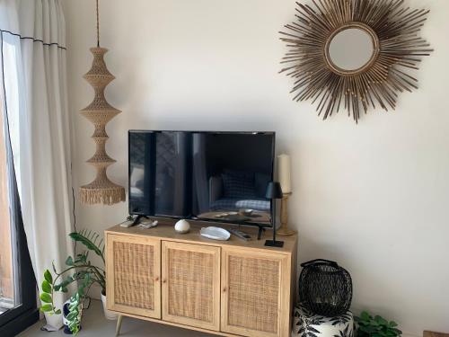a tv on a stand in a living room with a mirror at Front de mer 35m2 vue époustouflante in Carry-le-Rouet