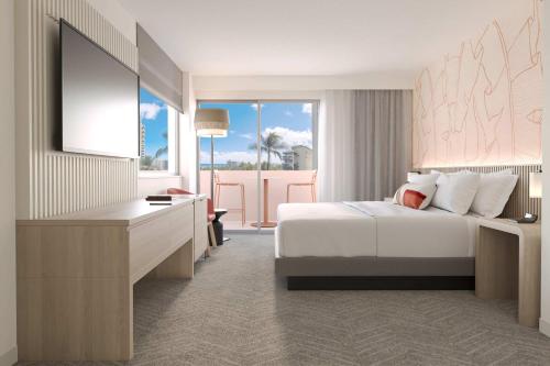 a bedroom with a bed and a desk and a television at The Ambassador of Waikiki, Tapestry Collection by Hilton in Honolulu