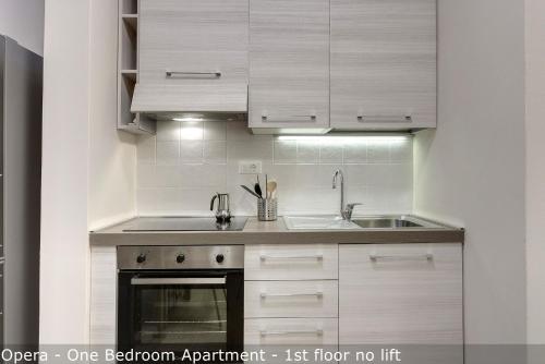 a kitchen with white cabinets and a sink at Opera - Sinfonia - Minuetto - Melody Apartments by Mamo Florence in Florence