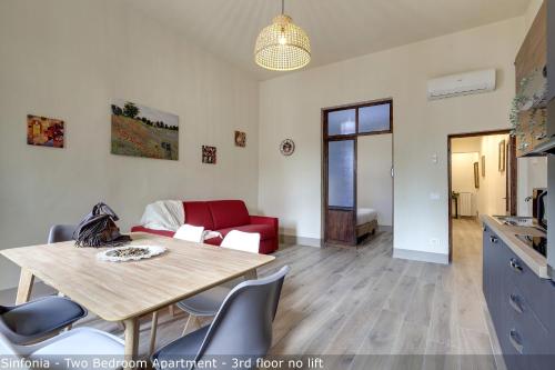a living room with a table and a red couch at Opera - Sinfonia - Minuetto - Melody Apartments by Mamo Florence in Florence