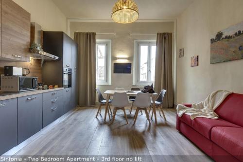 a living room with a red couch and a table and chairs at Opera - Sinfonia - Minuetto - Melody Apartments by Mamo Florence in Florence