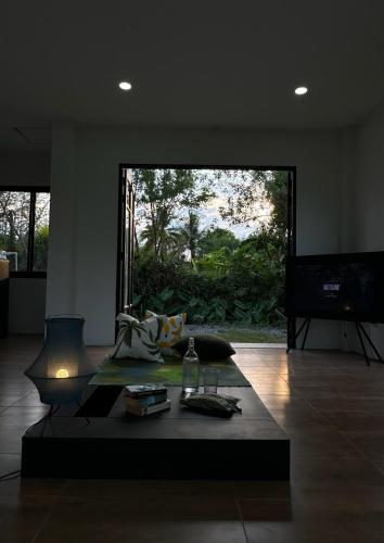 a living room with a coffee table and a large window at Waste Land Homestay & Resort Chiangmai in San Pa Tong