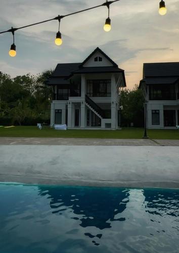 a house with a reflection in the water at Waste Land Homestay & Resort Chiangmai in San Pa Tong