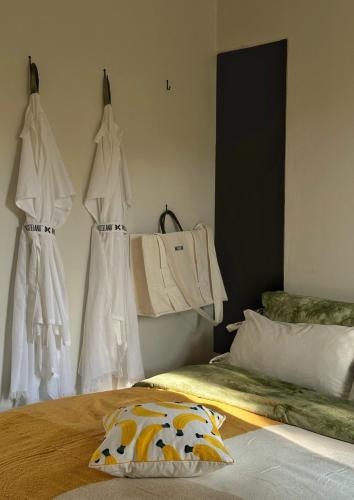 a bedroom with white dresses hanging on a wall at Waste Land Homestay & Resort Chiangmai in San Pa Tong