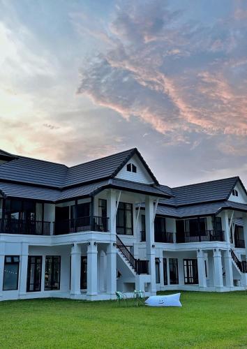 a large white building with a lawn in front of it at Waste Land Homestay & Resort Chiangmai in San Pa Tong