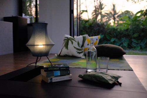 a table with a lamp and a bottle on it at Waste Land Homestay & Resort Chiangmai in San Pa Tong