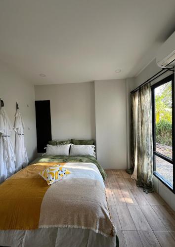 a bedroom with a large bed and a window at Waste Land Homestay & Resort Chiangmai in San Pa Tong