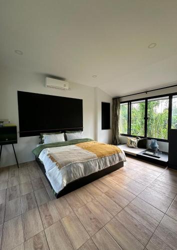 a bedroom with a large bed with a large flat screen tv at Waste Land Homestay & Resort Chiangmai in San Pa Tong