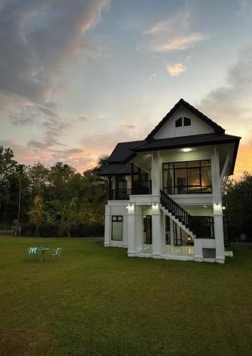 a house with a large yard with a sunset at Waste Land Homestay & Resort Chiangmai in San Pa Tong