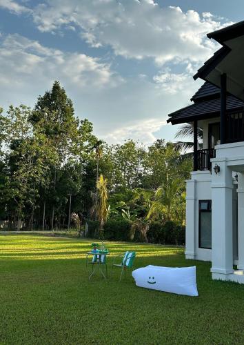 a table and two chairs and a surfboard on the grass at Waste Land Homestay & Resort Chiangmai in San Pa Tong
