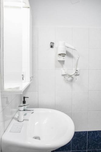 a white bathroom with a sink and a mirror at Solhouse in Gjirokastër