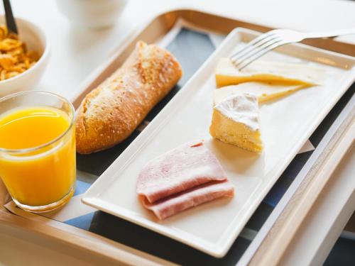 a tray with a plate of food and a glass of orange juice at ibis budget Caen Porte de Bretagne in Bretteville-sur-Odon