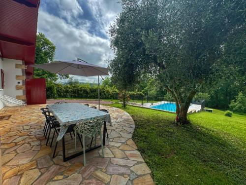 - une table avec un parasol sur une terrasse en pierre dans l'établissement Maison avec piscine, à Caro