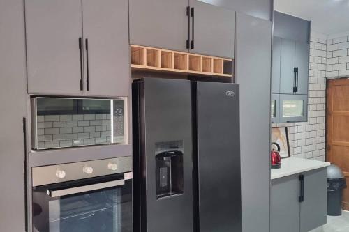 a kitchen with a stainless steel refrigerator and cabinets at Castletown Villa in Serowe
