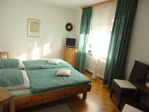 Schlafzimmer mit einem Bett mit grüner Bettwäsche und einem Fenster in der Unterkunft Ferienwohnung Toska in Pfaffenweiler