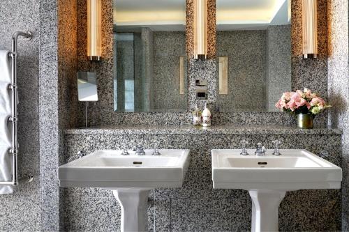 a bathroom with two sinks and a mirror and flowers at Haymarket Hotel, Firmdale Hotels in London
