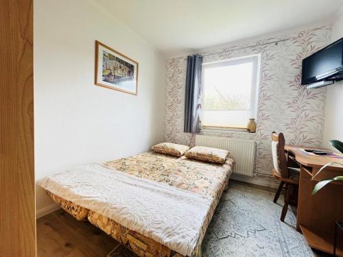 a small bedroom with a bed and a desk at Garten-Ferienhaus Biendorf OT Westenbrügge in Uhlenbrook