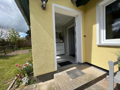 a yellow house with a door open to a yard at Garten-Ferienhaus Biendorf OT Westenbrügge in Uhlenbrook