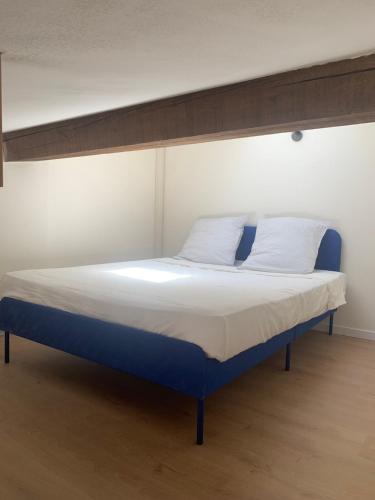 - un lit avec un cadre bleu et des draps et oreillers blancs dans l'établissement Appartement centre-ville Arles, à Arles