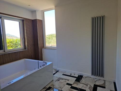 a bath tub in a bathroom with two windows at B&B Artemide in Agropoli