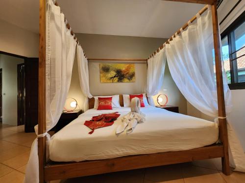 a bedroom with a canopy bed with white curtains at Soleil D'asie Residence in Chaweng Noi Beach