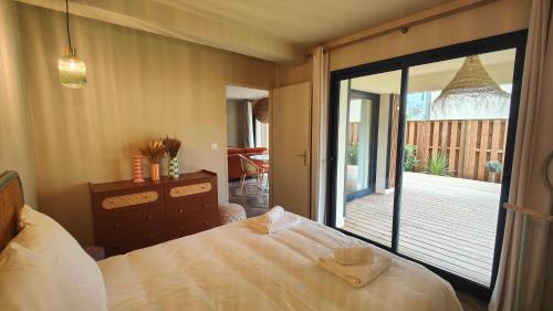 una camera da letto con un letto e una porta scorrevole in vetro di Appartement Jasmin Jacuzzi Piscine a Lacanau
