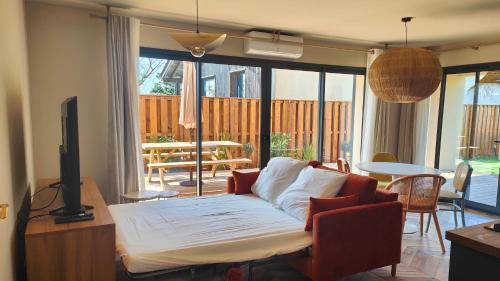 un salon avec un canapé, une télévision et une table dans l'établissement Appartement Jasmin Jacuzzi Piscine, à Lacanau