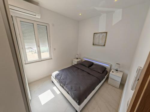 une chambre blanche avec un lit et une fenêtre dans l'établissement Petite villa climatisée Jardin, à Vallauris