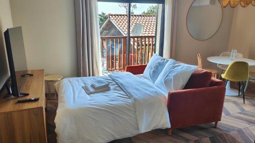 una camera da letto con un letto, una sedia e una finestra di L'appart Lila - Jacuzzi vue mer a Lacanau