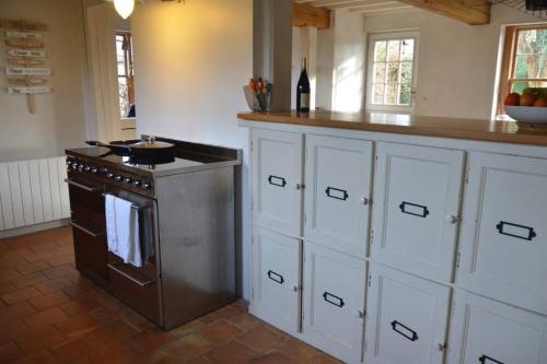 Il comprend une cuisine équipée d'une cuisinière, de placards blancs et d'un comptoir. dans l'établissement Séjour paisible maison de charme, à Gueutteville-les-Grès