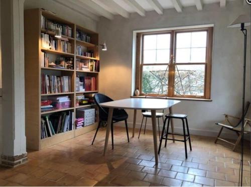 une pièce avec une table, des chaises et une étagère dans l'établissement Séjour paisible maison de charme, à Gueutteville-les-Grès
