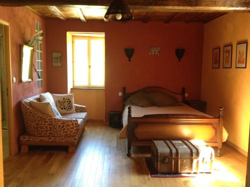 - une chambre avec un lit et une chaise avec une valise dans l'établissement Maison Balette, à Escou