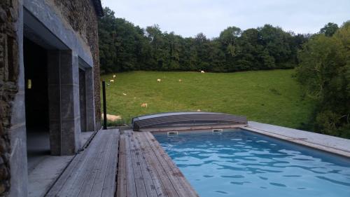 une piscine sur une terrasse avec un champ de vaches dans l'établissement Maison Balette, à Escou
