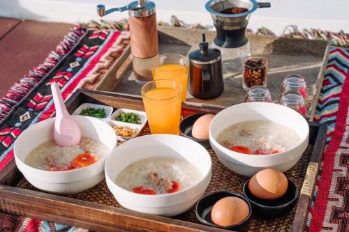 un plateau avec des bols de soupe, des œufs et des boissons dans l'établissement บ้านพักภูวิววิลล่า, à Ban San Pu Loei