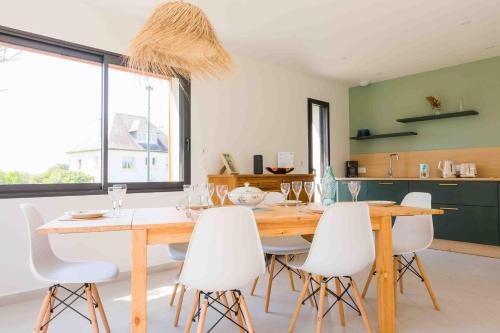 une salle à manger avec une table en bois et des chaises blanches dans l'établissement À 490m de la plage, maison neuve pour 8, à Trégunc