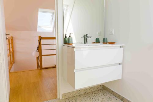 a white bathroom with a sink and a mirror at À 490m de la plage, maison neuve pour 8 in Trébérouant