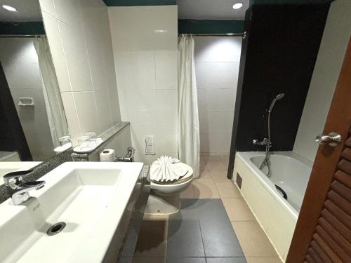 a bathroom with a sink and a toilet and a tub at Aloha Hatyai Hotel in Hat Yai